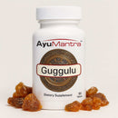 Guggulu Tablets bottle with guggulu resin pieces on white background, AyuMantra dietary supplement.