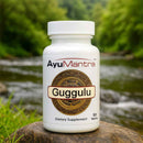 AyuMantra Guggulu Tablets bottle on a rock by a river, outdoor lifestyle product photo