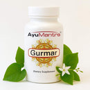 Gurmar Tablets bottle with green gurmar leaves and white flower on clean background, dietary supplement.